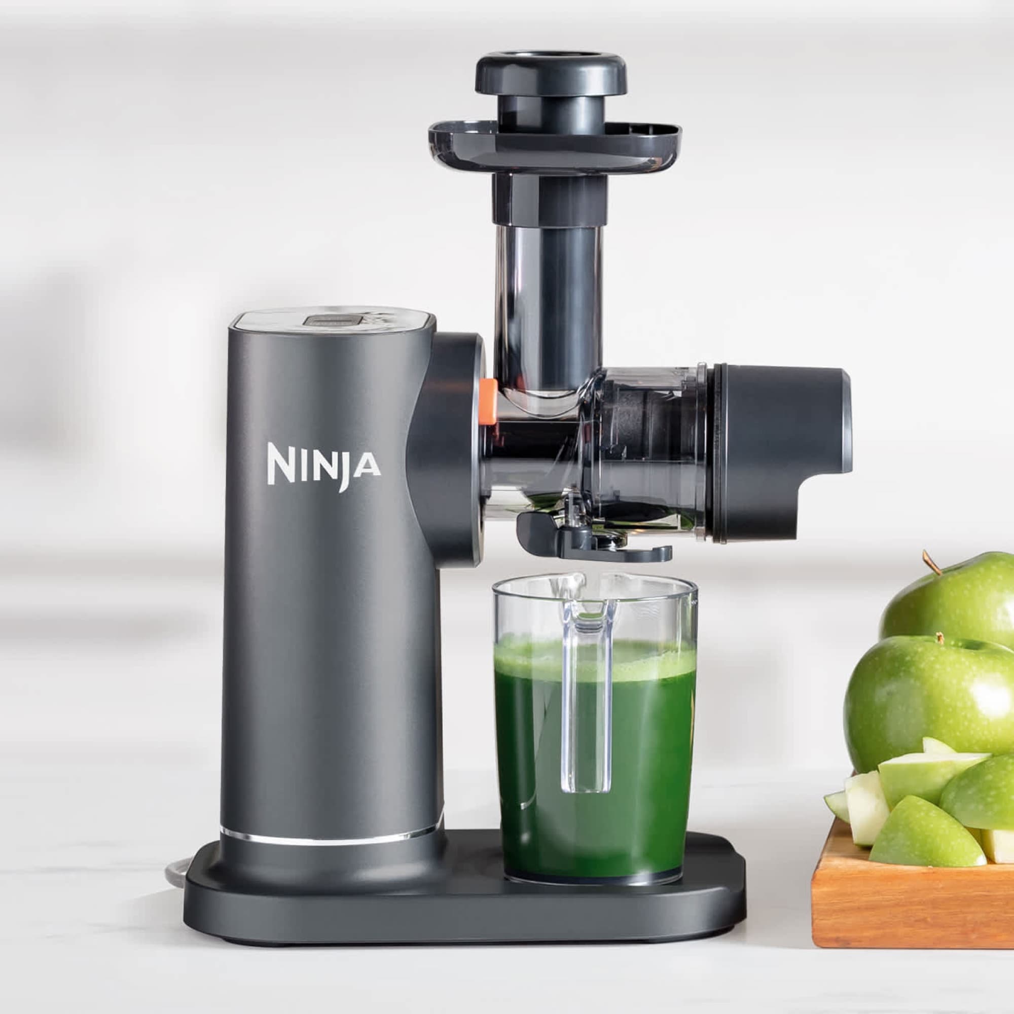 Grön juice i kannan bredvid äpplen