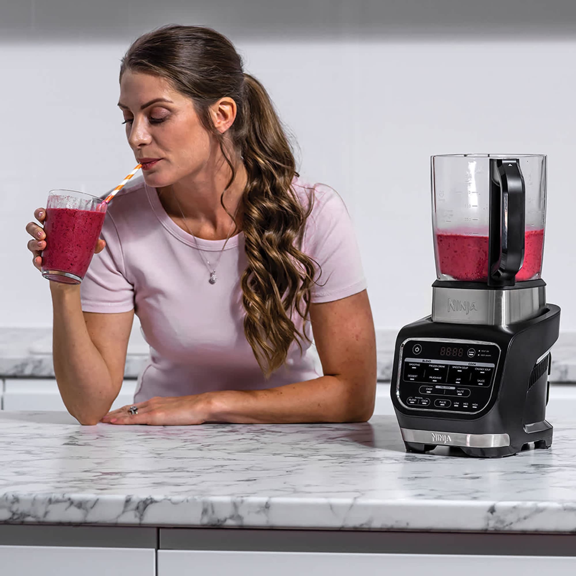 Berry smoothie in a glass next to the blender