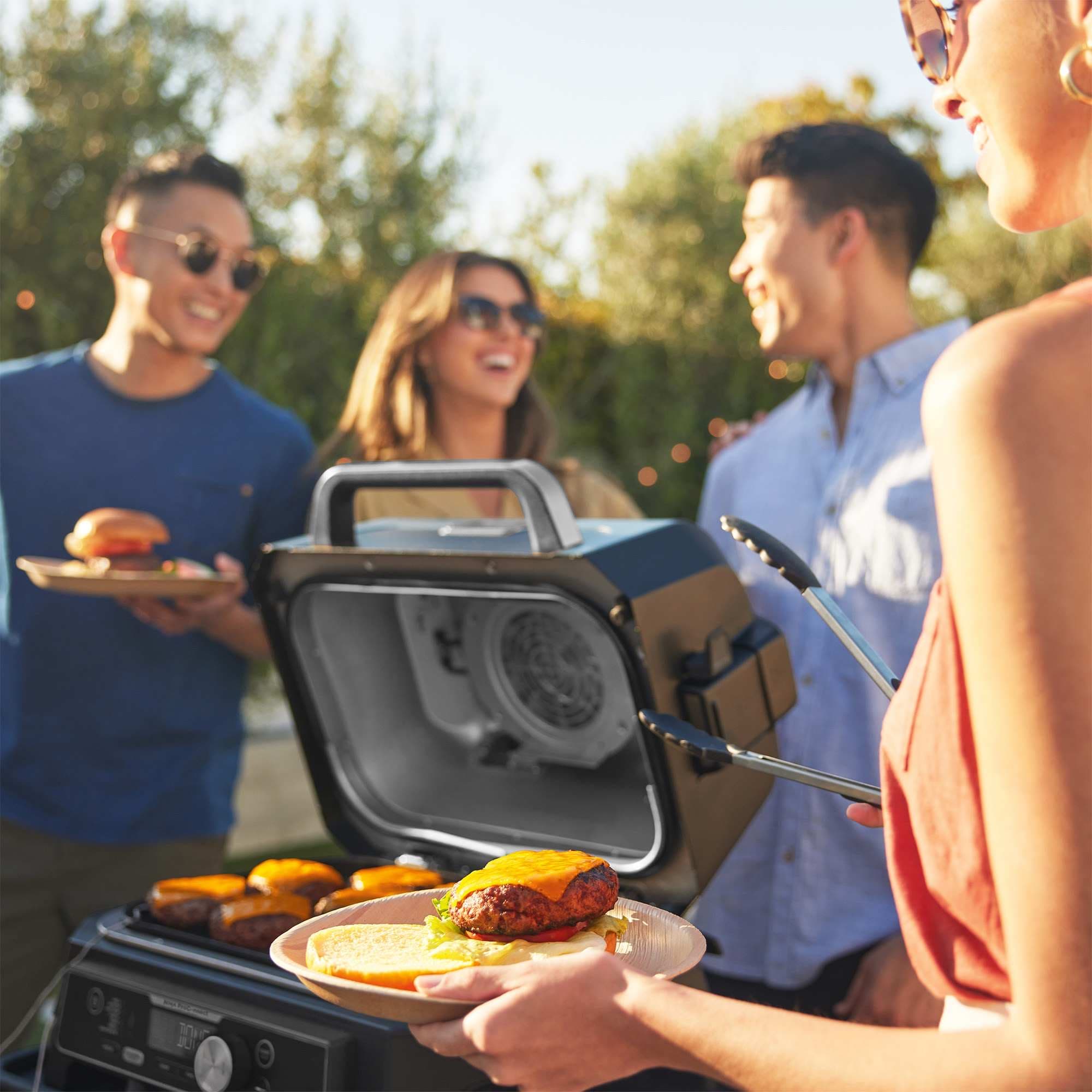 Vänner grillar burgare i trädgården