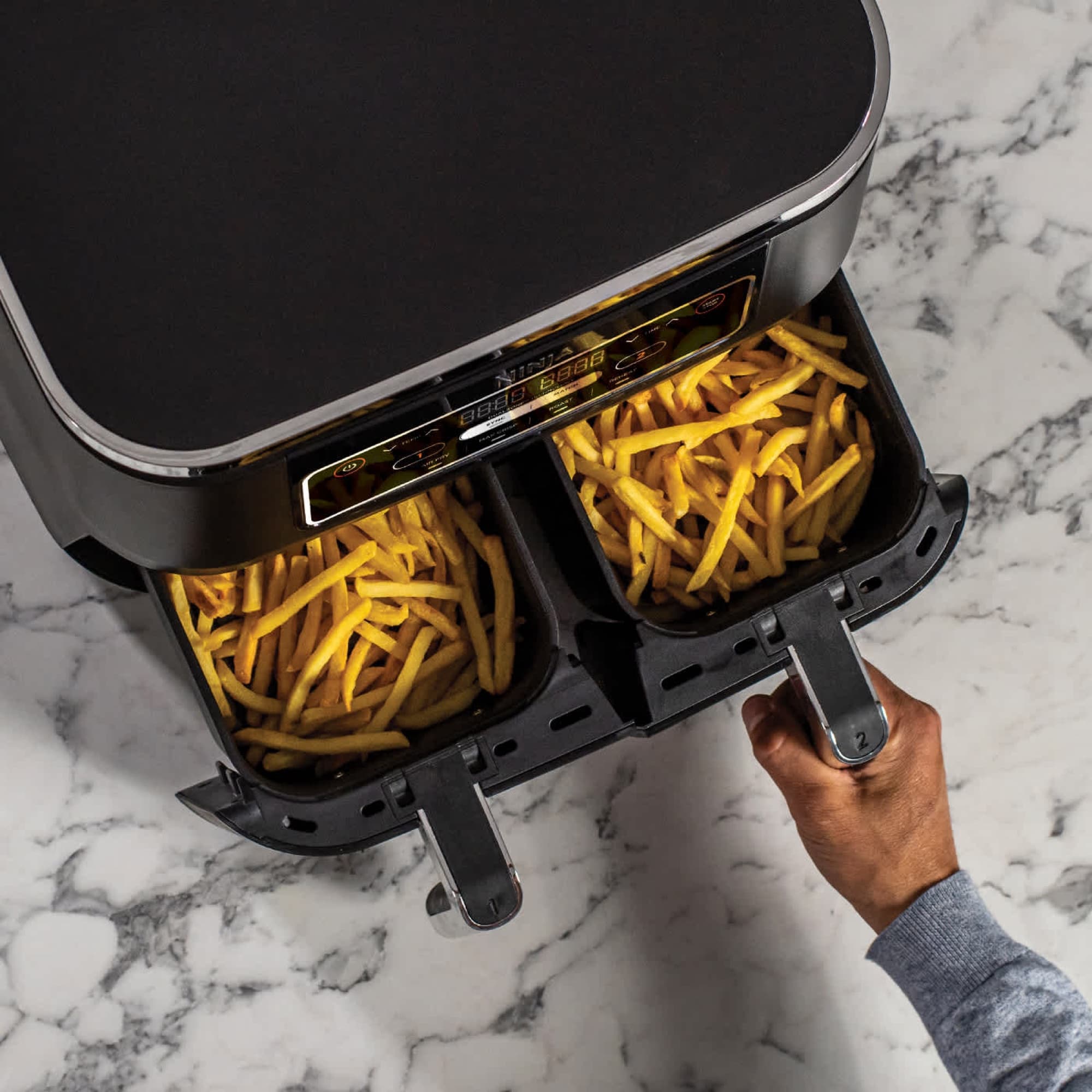 Hand som drar ut två lådor med pommes frites
