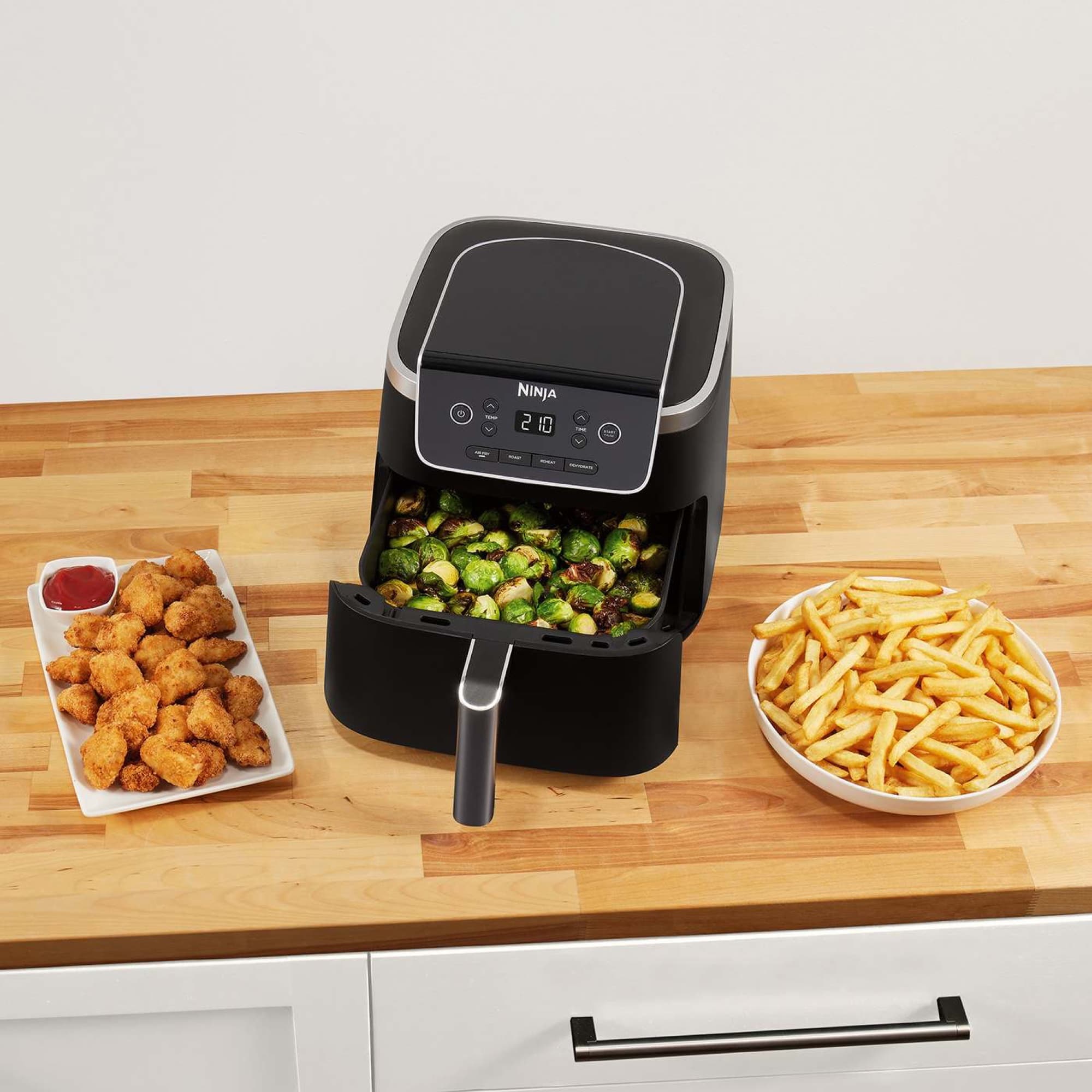 Öppen låda med brysselkål, bredvid ett fat pommes och friterad kyckling